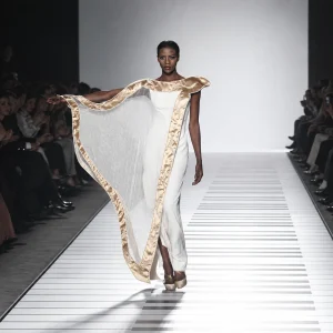 Jamal Taslaq, abito bianco con mantello bordato d'oro, in passerella